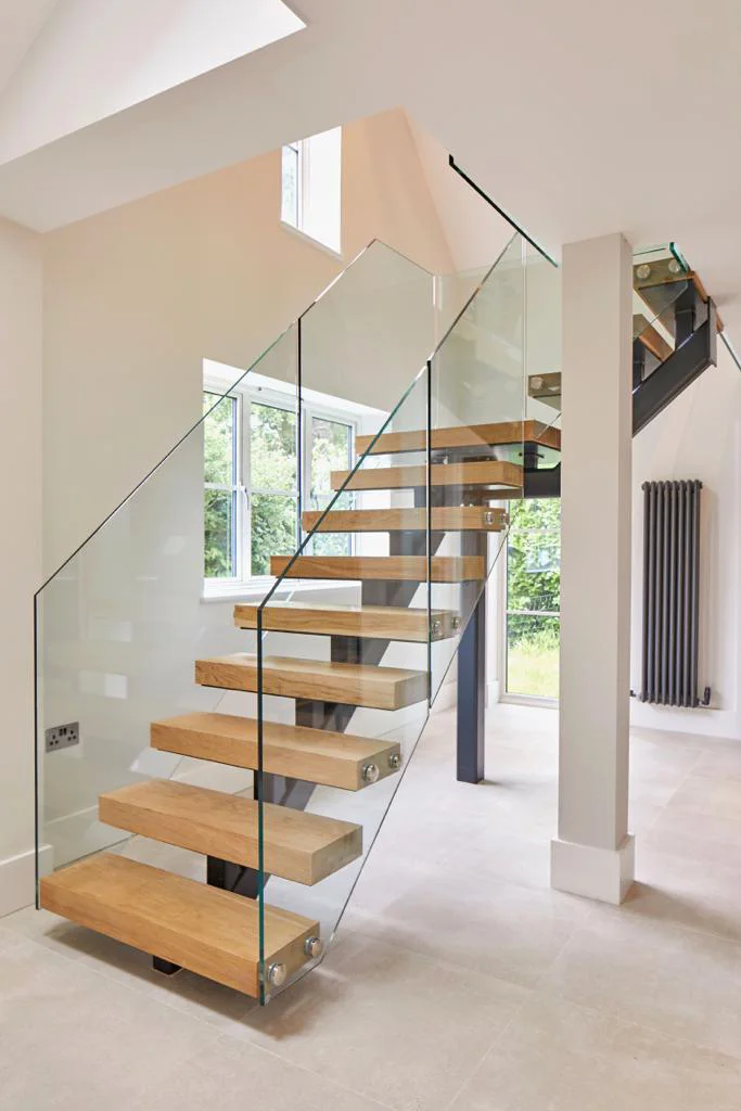 A stunning wooden, levitating staircase with glass sides in a very modern space.